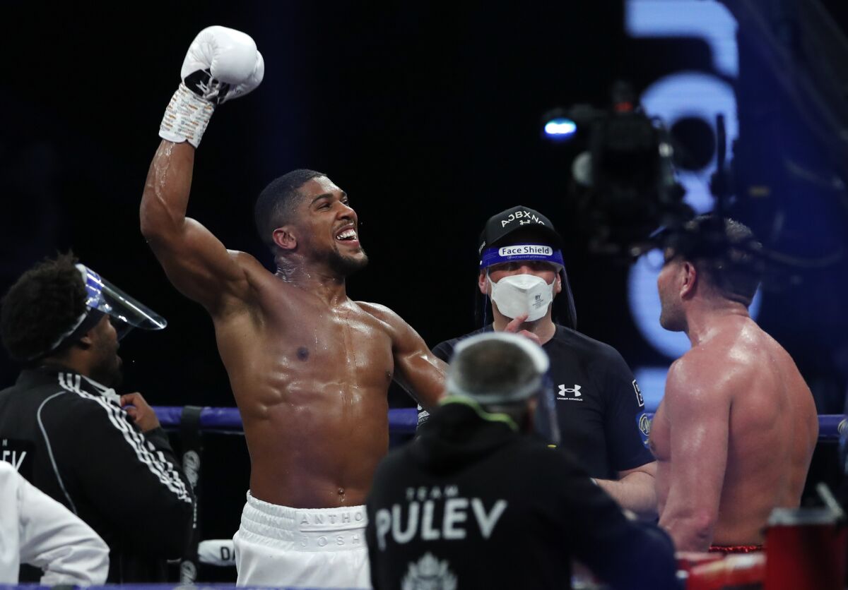 Anthony Joshua, left, celebrates after beating Kubrat Pulev in their heavyweight title fight in London on Dec. 12, 2020.