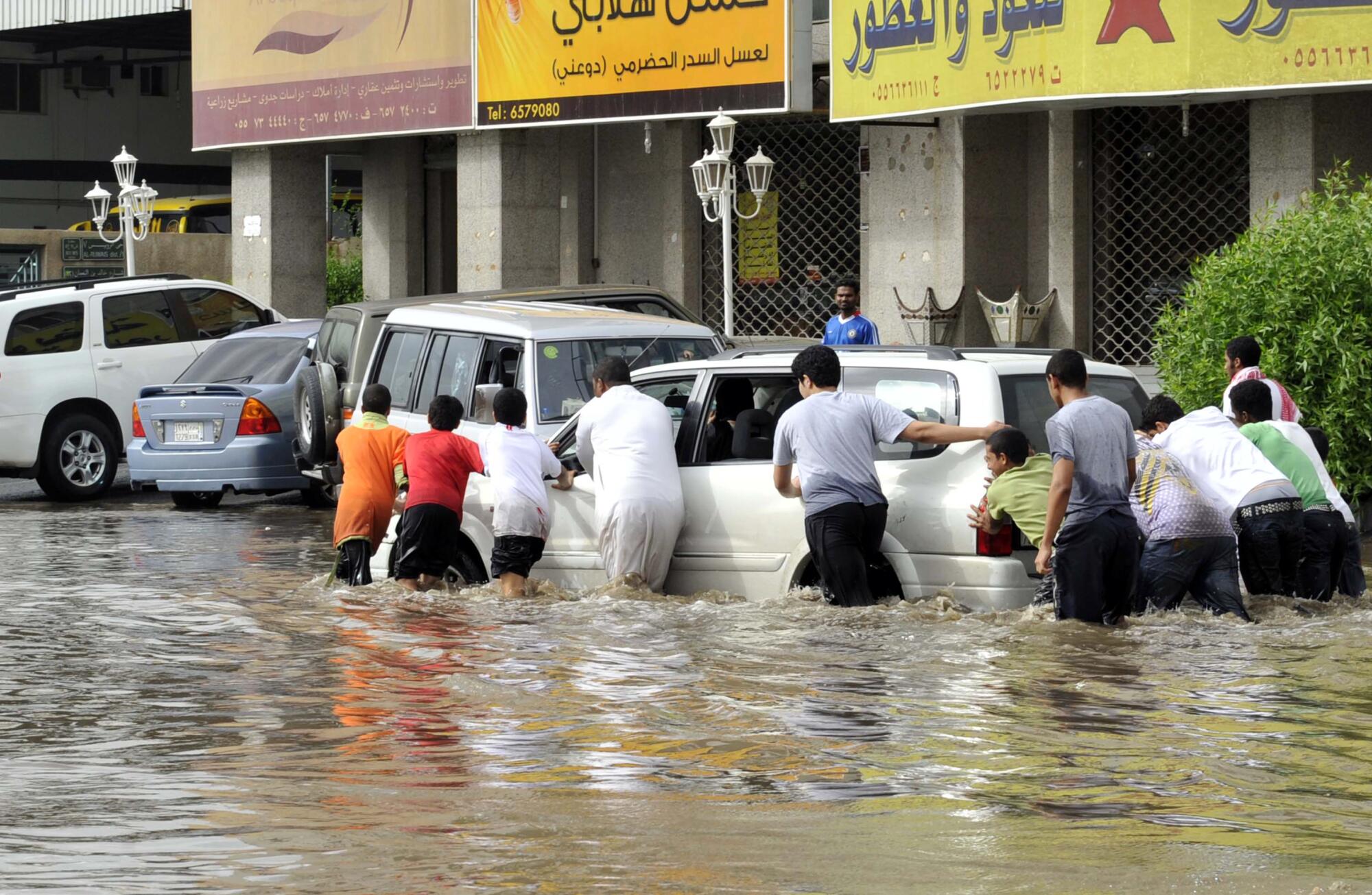 Men pushing a car stuck in a flooded street