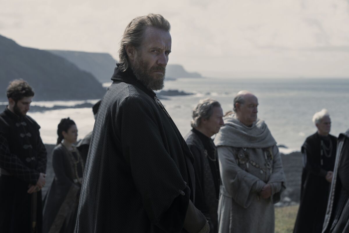 a man in a cloak standing near a crowd