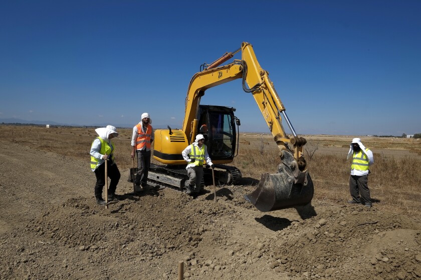 FILE - A bulldozer and workers of Cyprus Missing Persons of the two communities work together during an excavation in a field for missing persons in the Turkish breakaway northern part of divided capital Nicosia, Cyprus, May 31, 2017. U.S. academics who help locate Holocaust mass graves and execution sites in Eastern Europe have used high-tech, ground-penetrating radar to identify potential burial sites of people who disappeared amid war in Cyprus nearly a half century ago. (AP Photo/Petros Karadjias, File)