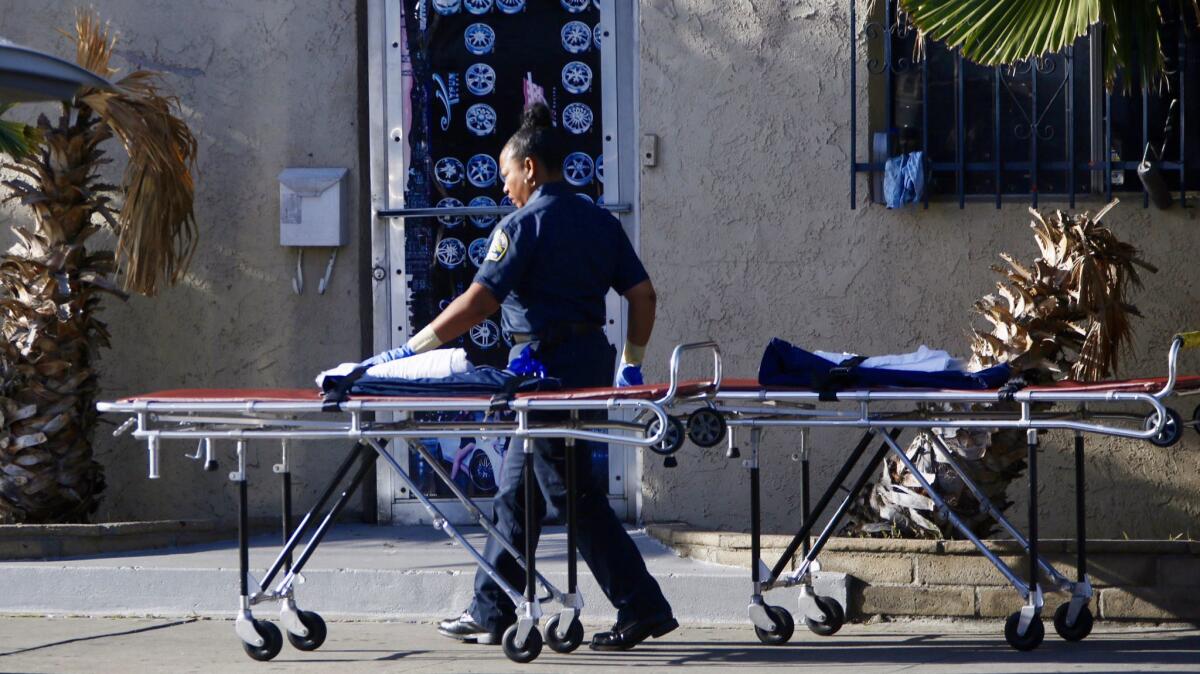 The Los Angeles County Coroner arrives with two gurneys outside First Class Audio in Downey Tuesday morning, after a shootout left two dead and a third man injured.