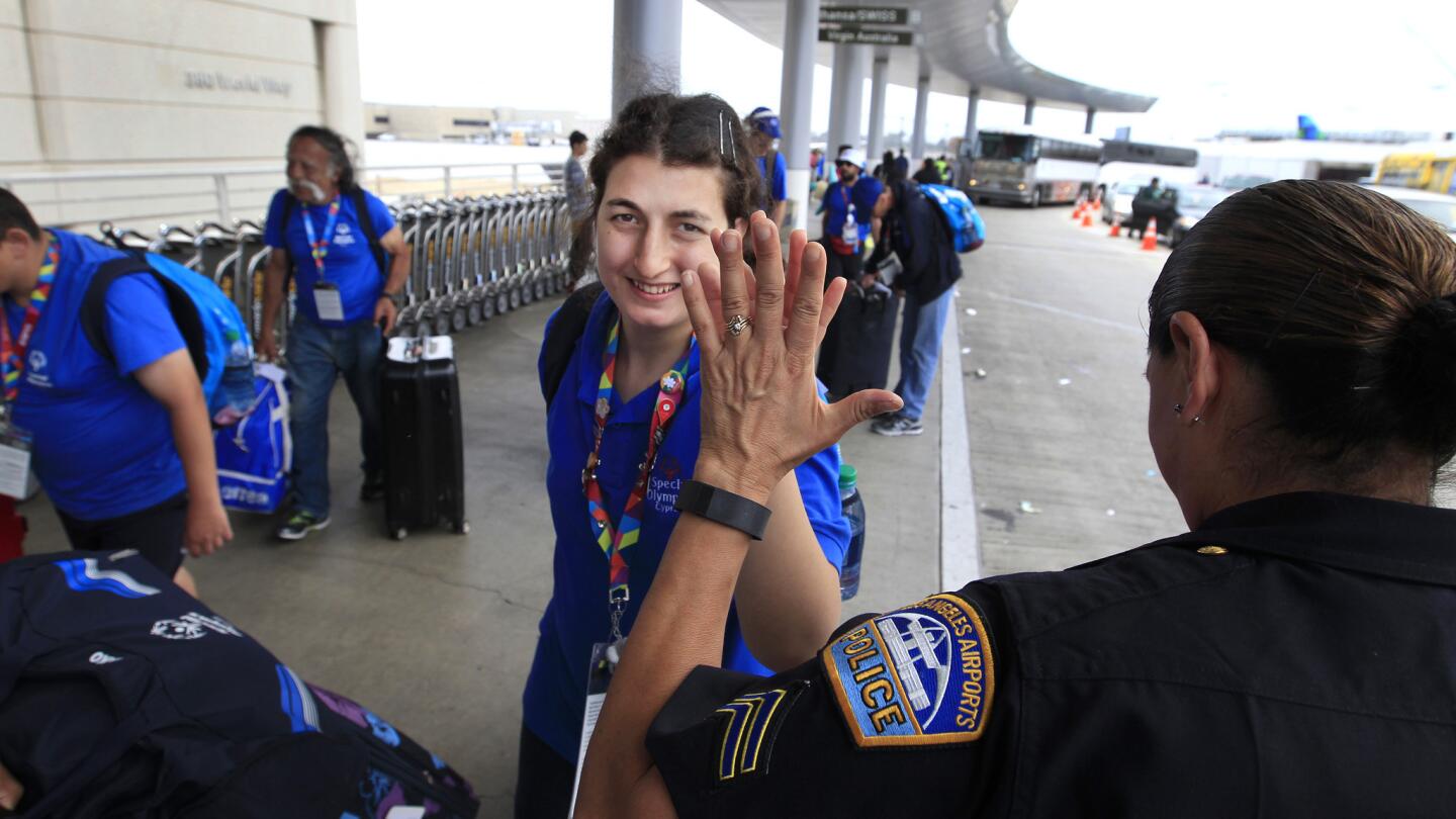 LAX Airport Police Officer Adela Lopez high-fives a Special Olympics athlete from Cyprus as they head into the Tom Bradley Terminal at Los Angeles International Airport to catch a flight home on Monday.