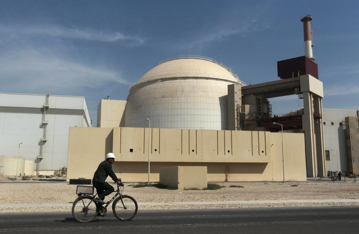 A worker rides a bicycle in front of the reactor building of the Bushehr nuclear power plant in Iran.
