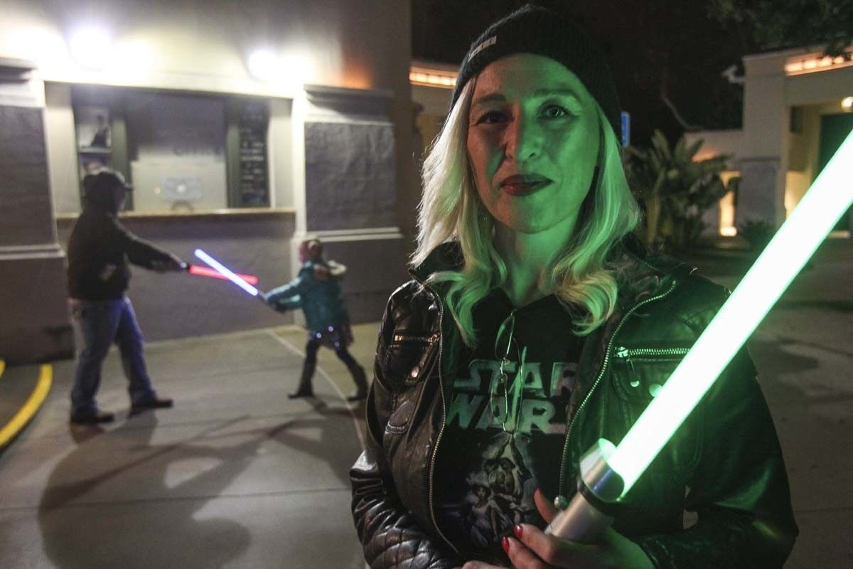 Angela Brittain, from Oceanside, holds her lightsaber as her husband Josh Brittain and daughter Ellie, 6, play with theirs as they and other Star Wars fans gather at the California Center for the Arts, Escondido to pay tribute to actress Carrie Fisher on Dec. 30, 2016. (Hayne Palmour IV/U-T)
