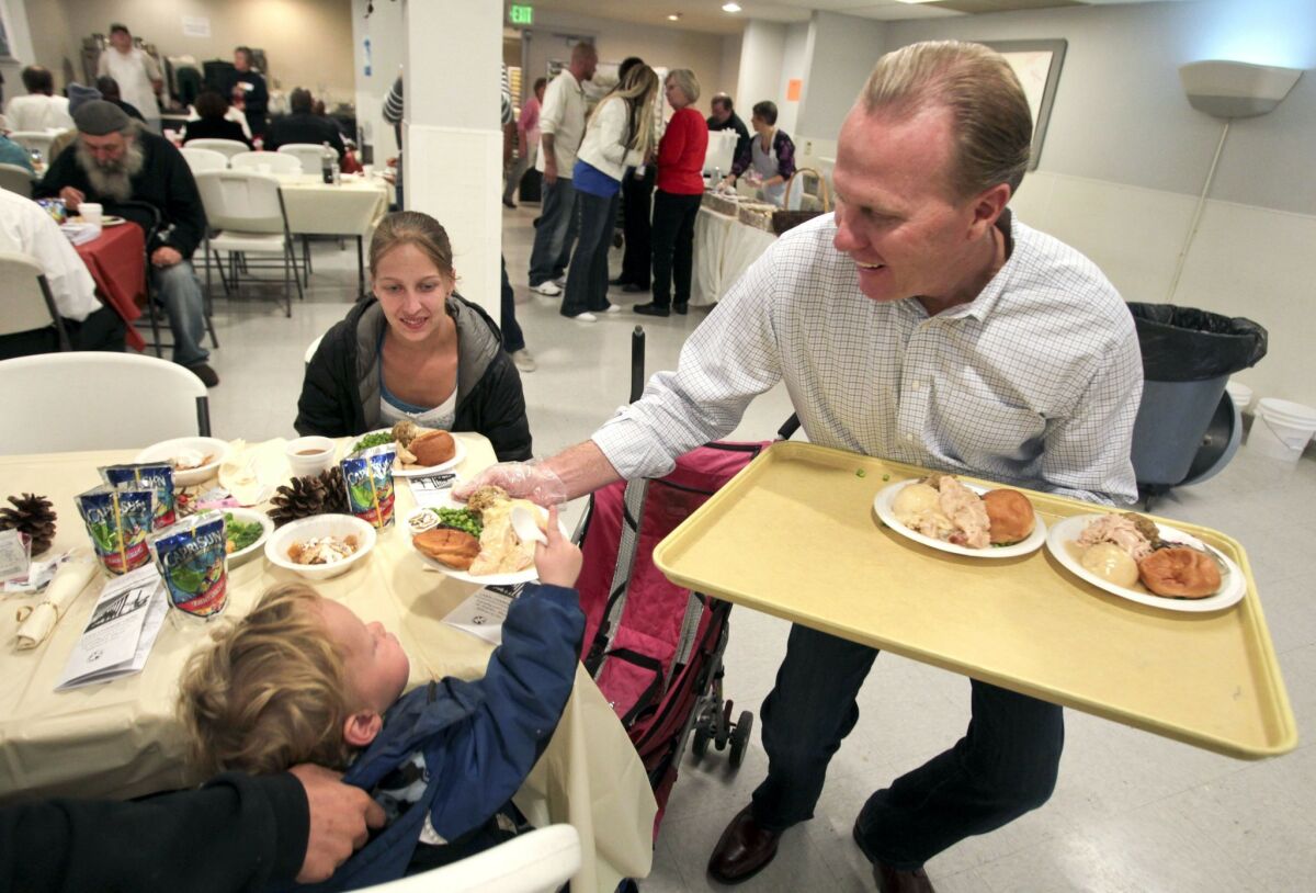 San Diego mayoral candidate Kevin Faulconer serves a turkey meal to 2-year-old Dustin Fry during the San Diego Rescue Mission's annual Thanksgiving dinner. — Hayne Palmour IV