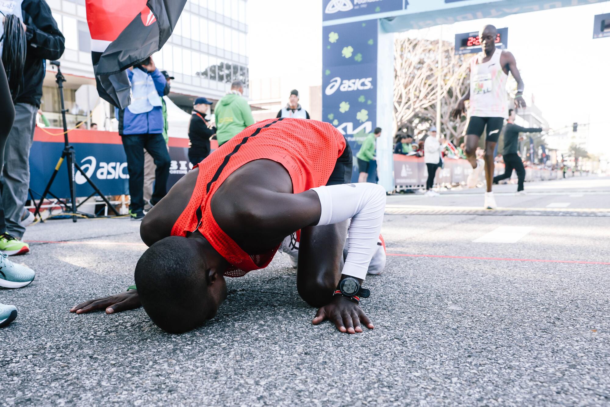 Dominic Ngeno while on his hands and knees kisses the street after winning. 