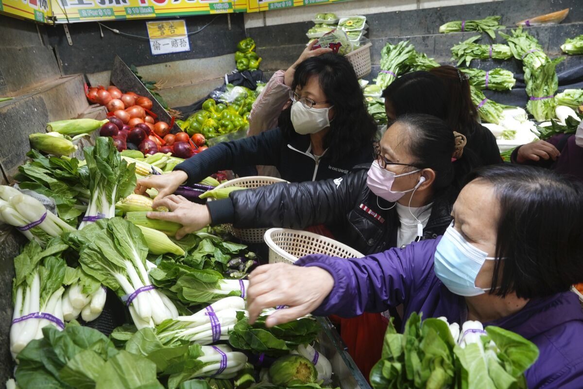 Customers wearing face masks buy fresh vegetable at a wet market store in Hong Kong, Wednesday, Feb. 9, 2022. Hong Kong's leader announced on Tuesday the city's toughest social-distancing restrictions yet, including unprecedented limits on private gatherings, as new daily cases surge above 600. (AP Photo/Vincent Yu)