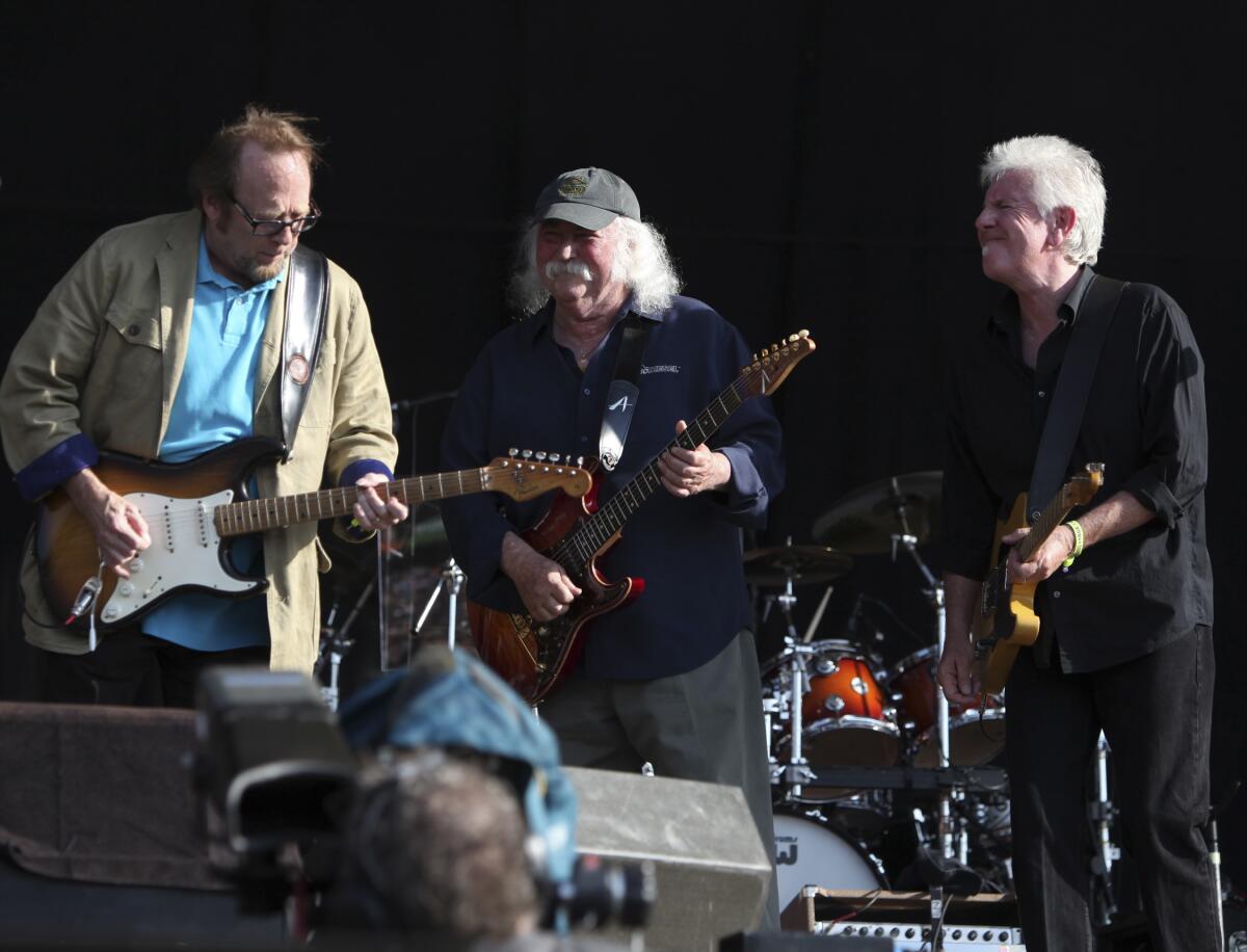 Three men on a stage holding guitars for a performance on stage