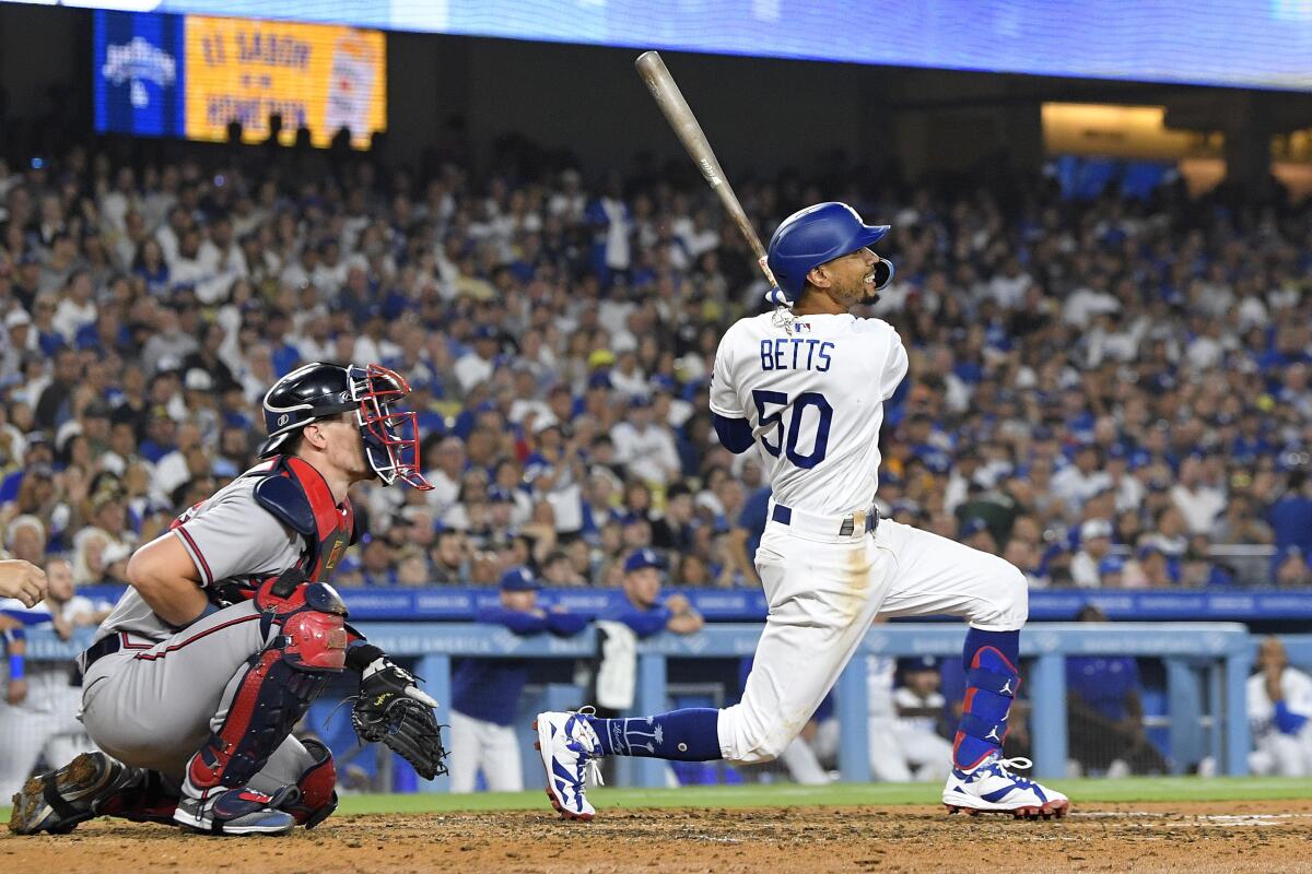 The Dodgers' Mookie Betts hits a three-run home run as Braves catcher Sean Murphy watches 