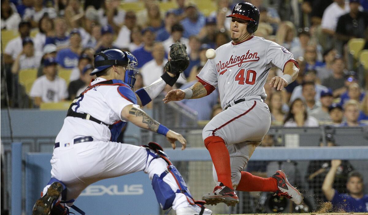 Washington Nationals' Wilson Ramos, right, slides into home plate as he tries to score on a single by Tanner Roark while Dodgers catcher Yasmani Grandal awaits the throw before tagging out Ramos during the eighth inning Tuesday.