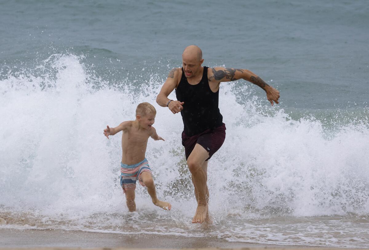 A man and a boy run in the surf.