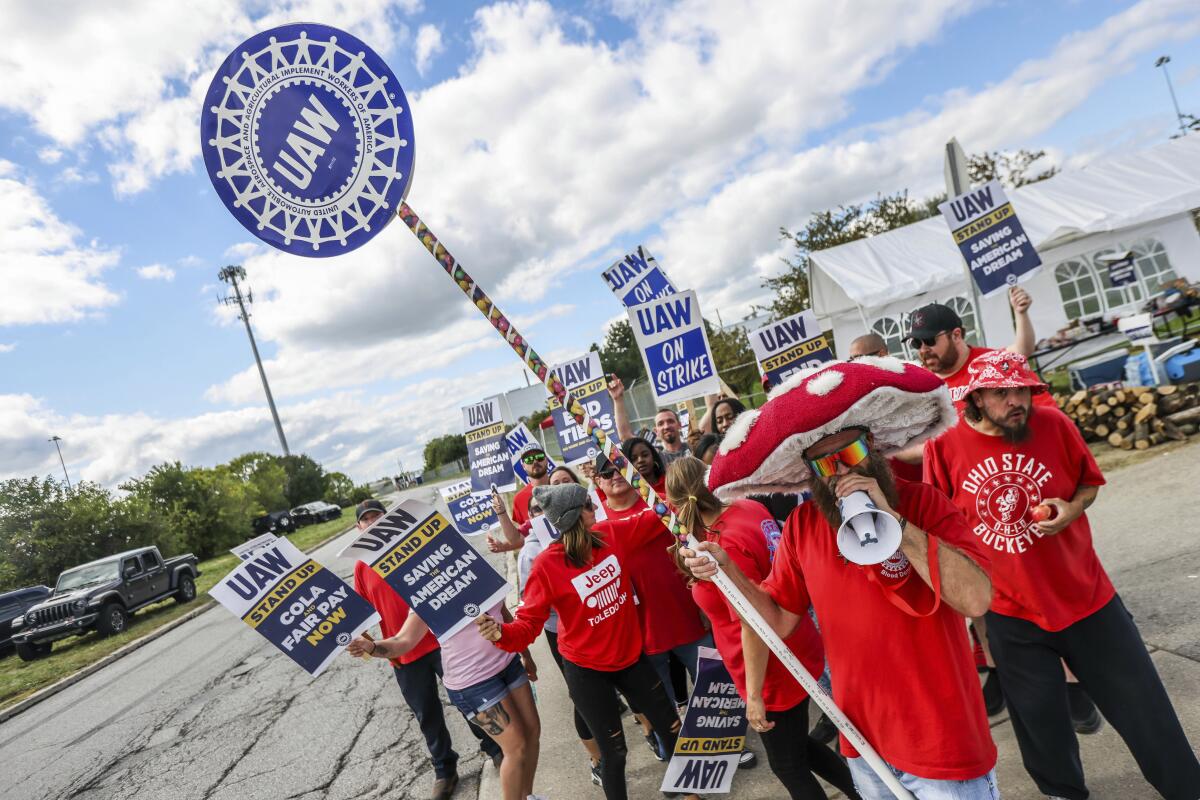 Workers hold UAW signs while picketing.