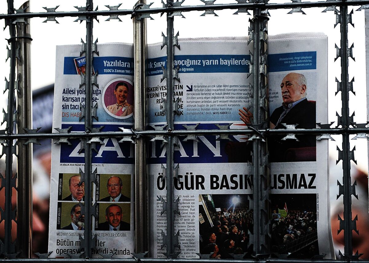 A supporter holds a copy of the Turkish newspaper Zaman behind a fence as police arrest its editor in chief in Istanbul on Sunday.