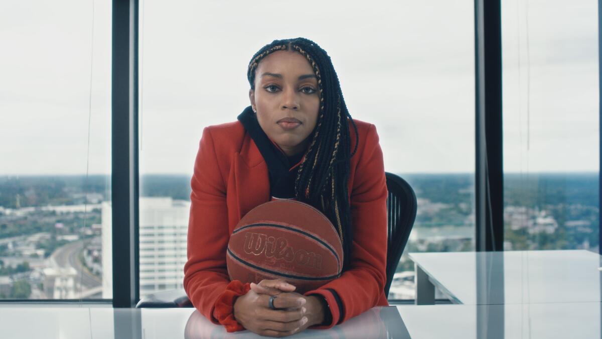 Una mujer con una pelota de baloncesto mira a la lente.