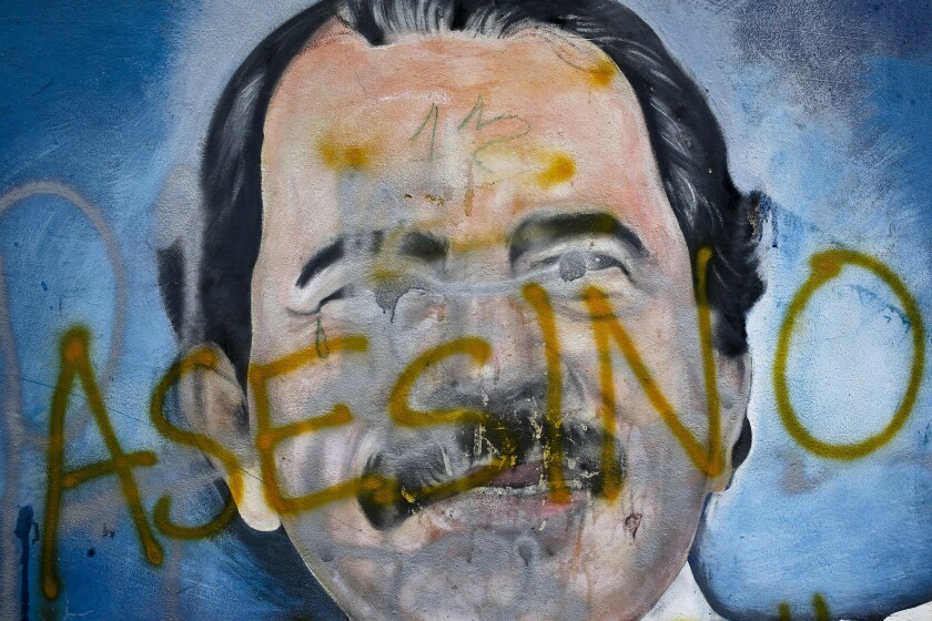 FILE - The Spanish word for "Murderer" covers a mural of Nicaragua's President Daniel Ortega, as part of anti-government protests demanding his resignation in Managua, Nicaragua, May 26, 2018. Four months before scheduled 2022 municipal elections, Nicaraguan riot police have taken over the city halls of five municipalities that had been in the hands of an opposition party. (AP Photo/Esteban Felix, File)