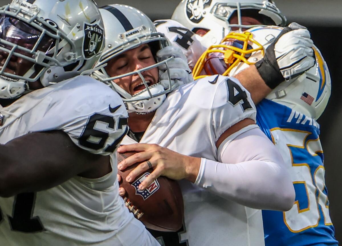 Raiders quarterback Derek Carr (4) is about to be overtaken by Chargers linebacker Khalil Mack (52), who forced a fumble.