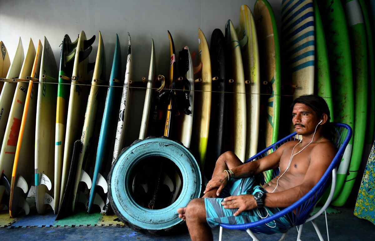 a man sits with surfboards behind him