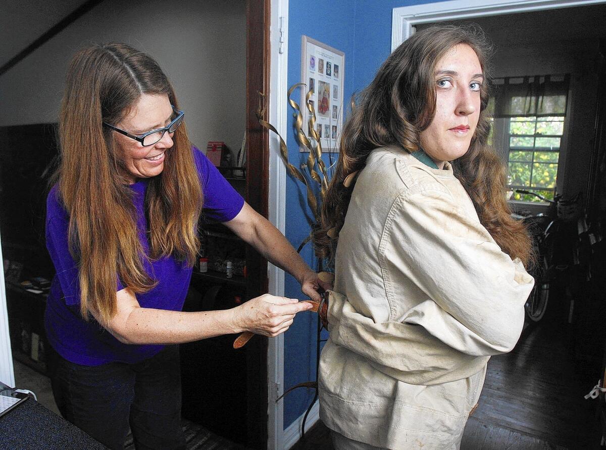 London Ruff, 17, of Burbank,is secured into a straight jacket by her mom, Wendy, in her home on Monday, March 3, 2014. Professionals are mentoring Ruff in the Magic Castle program. She will perform at Providence High School to raise money for the school. One of her magic specialties is escaping from a straight jacket.