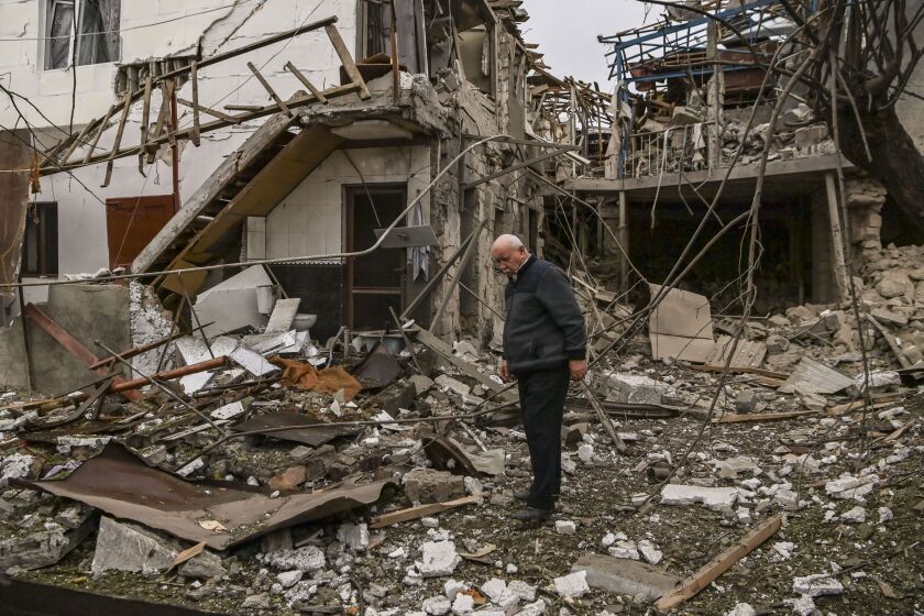 An elderly man stands in front of a destroyed house in the Nagorno-Karabakh region's main city of Stepanakert.