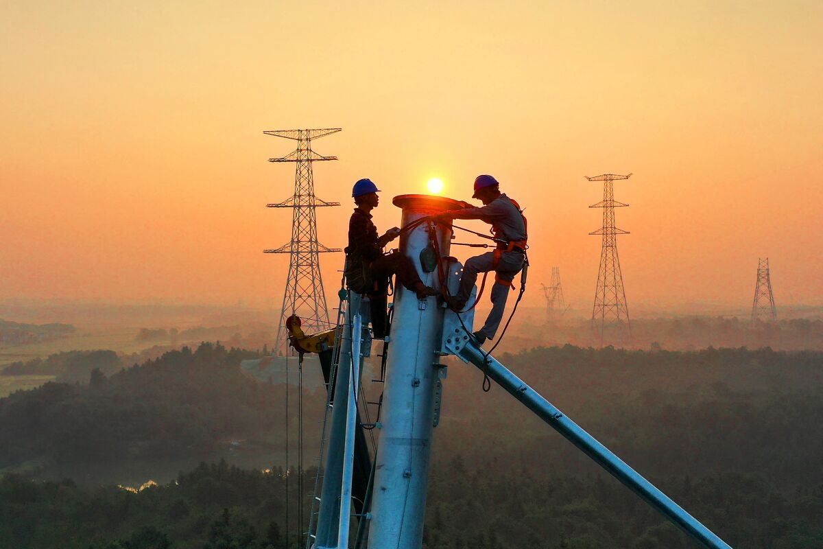 Employees work on a high-voltage transmission tower in China.