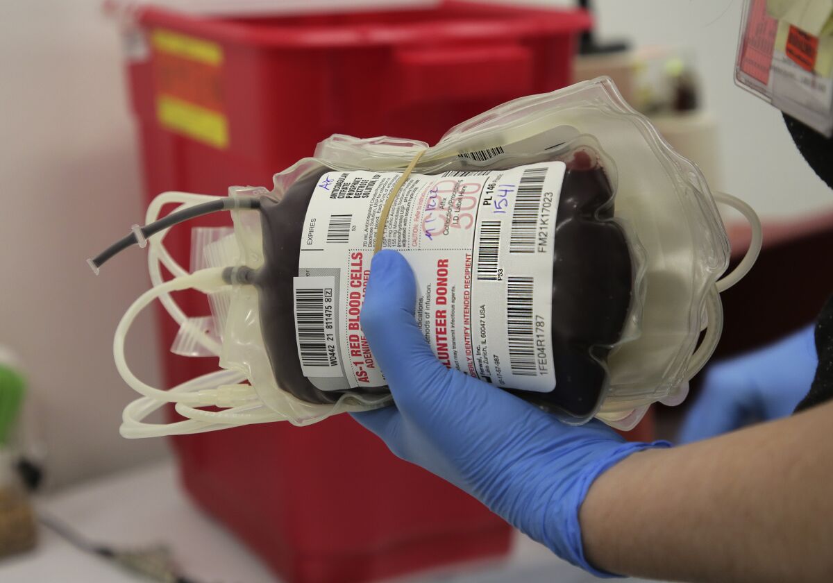 A technician carries donated pints of blood collected at the Liberty Station Donor Center on Wednesday.