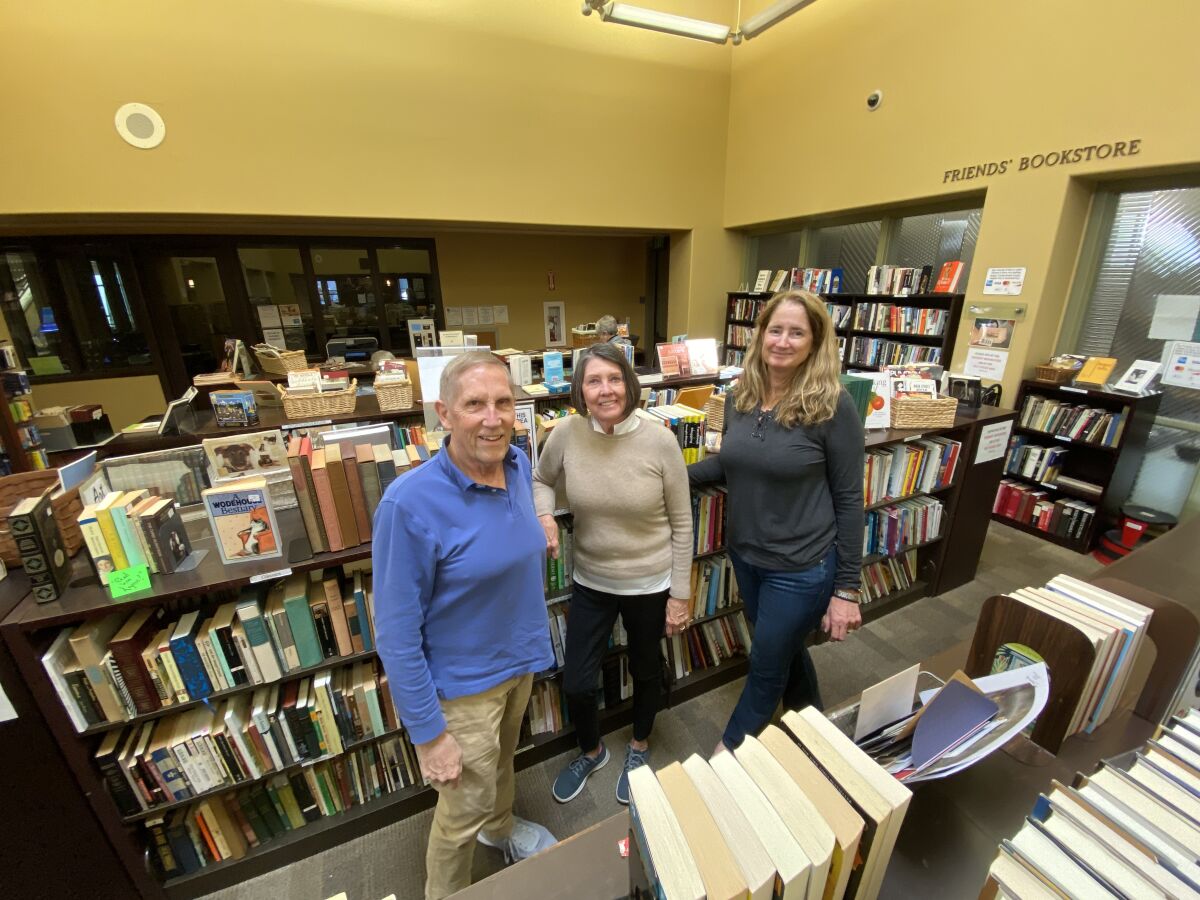 Volunteers Jim Stewart, Suzanne Weiner and Kara Farley pose in front of some of the hundreds of books they have for sale at the Friends of La Jolla Library bookstore, 7555 Draper Ave.