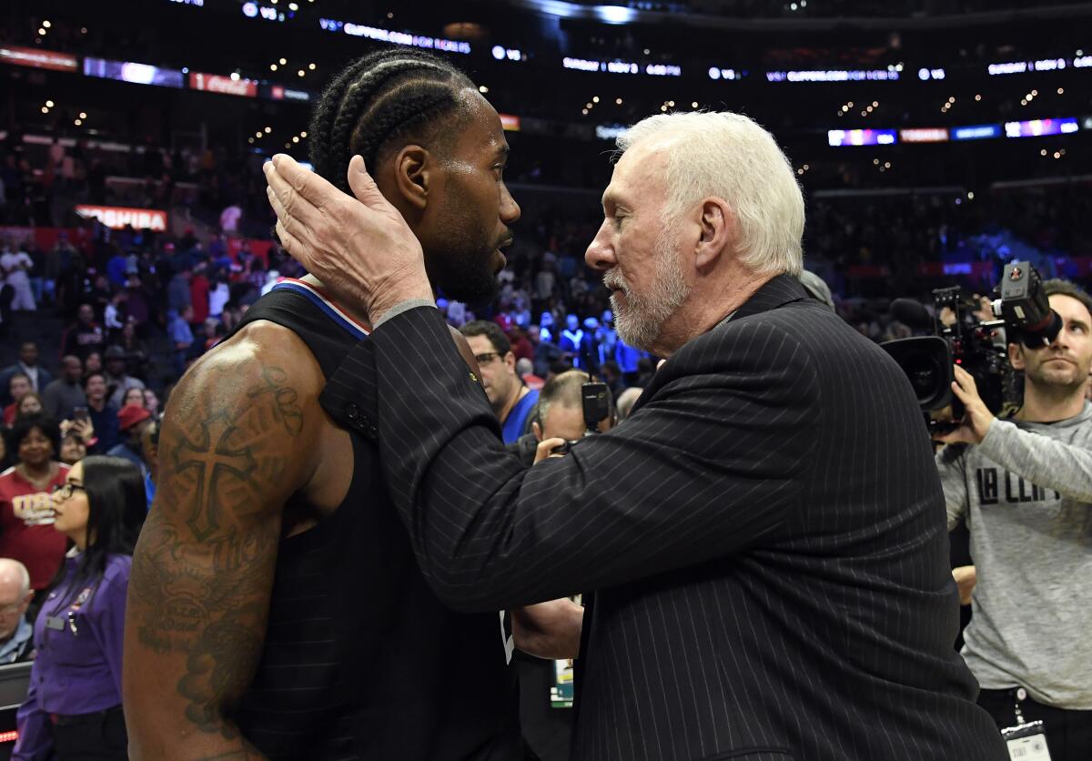 Clippers forward Kawhi Leonard gets a hug from his former head coach, Gregg Popovich, after scoring a game-high 38 points against the Spurs on Thursday at Staples Center.