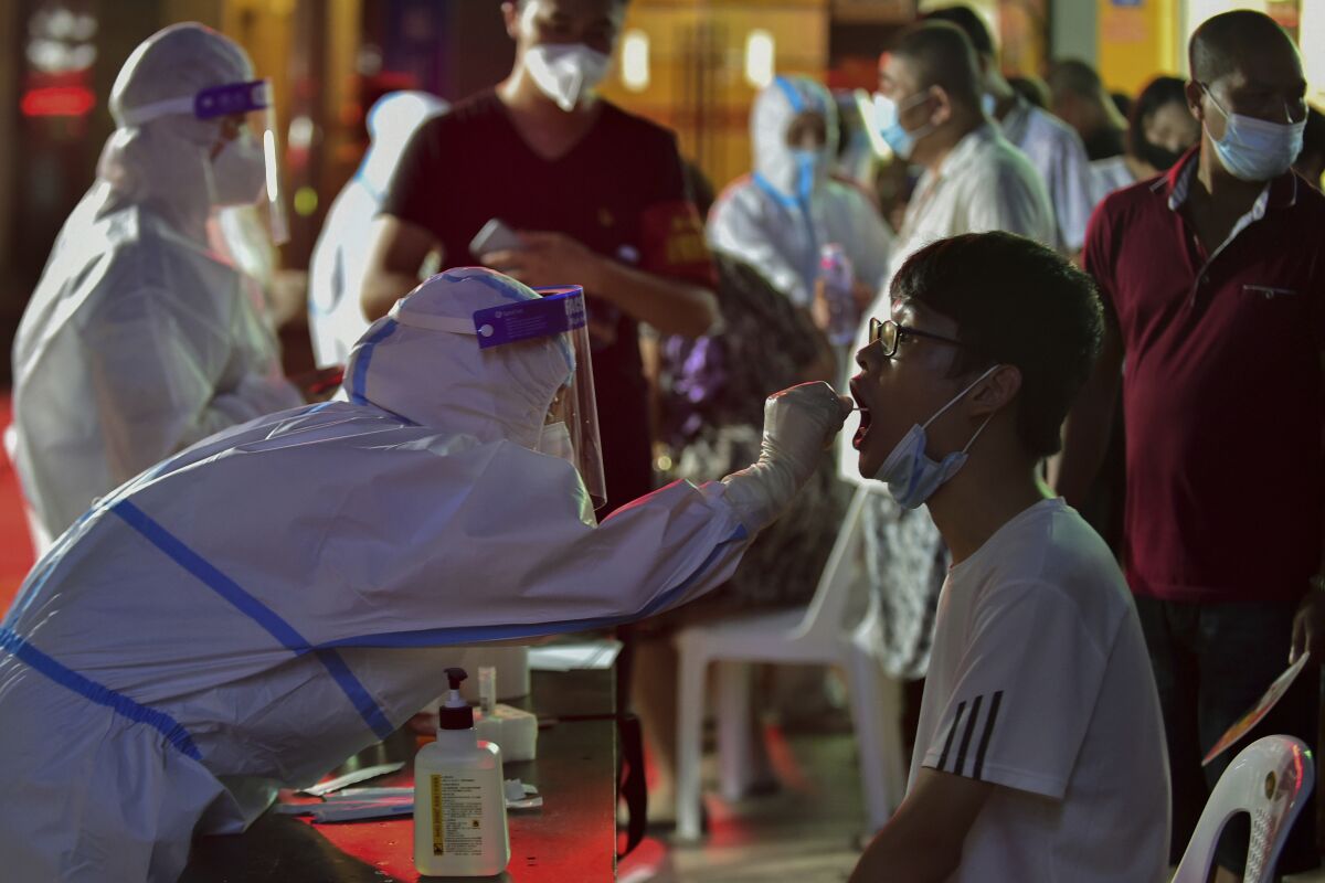 In this photo released by Xinhua News Agency, a health worker collects swab sample from a resident during a mass COVID-19 test in Putian in southeast China's Fujian province on Sunday, Sept. 12, 2021. Putian, a city in southern China that is trying to contain a coronavirus outbreak told the public Sunday not to leave, suspended bus and train service and closed cinemas, bars and other facilities. (Wei Peiquan/Xinhua via AP)
