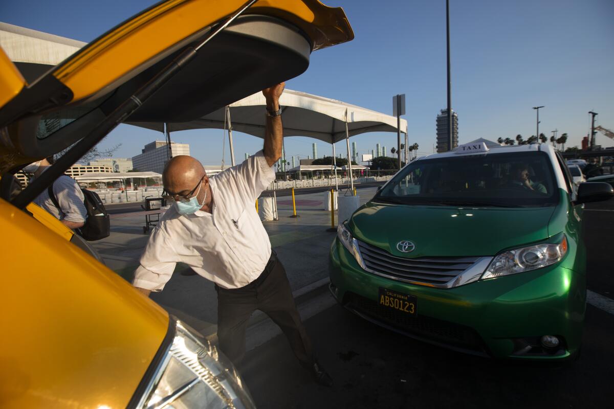 Anoushavan Setagaya places luggage in the trunk for a departing passenger.