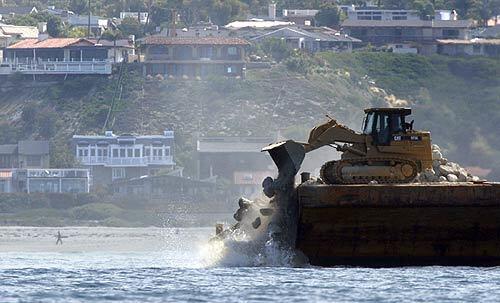 A giant skip loader drops a load of rocks into the waters off San Clemente as part of a reef construction project by Southern California Edison. The reef is a long-planned mitigation measure to protect marine life affected by the San Onofre nuclear plant.