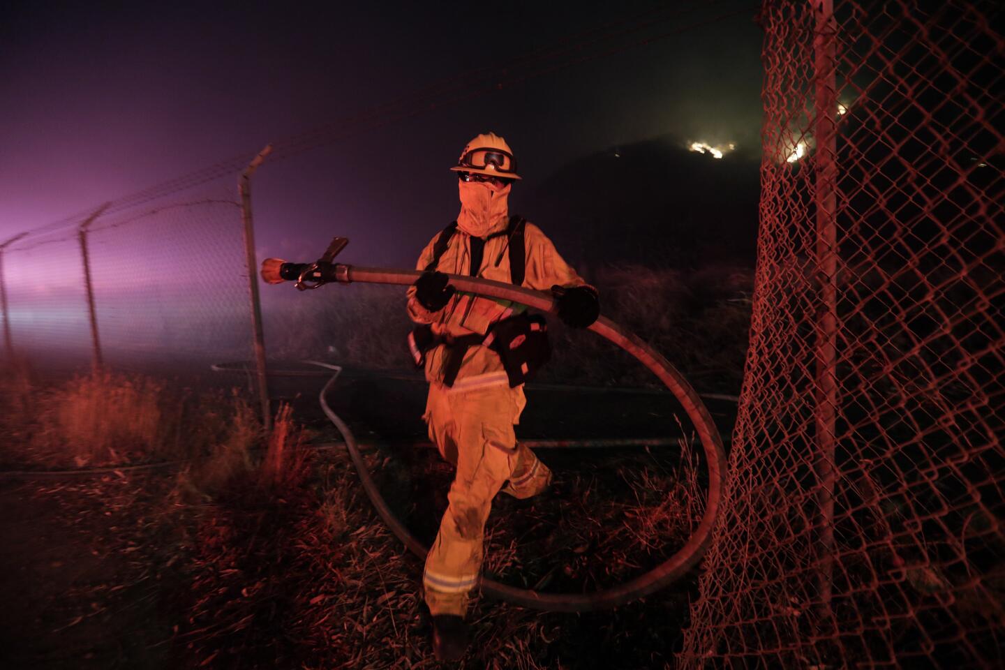 A Newport Beach firefighter prepares to leave the scene as Los Angeles County firefighters move in on the Castlewood fire.