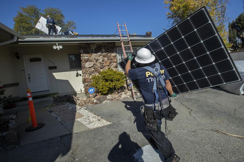 GRANADA HILLS, CA - JANUARY 04, 2020: Luis Jimenez, lead installer for the solar company, Sunrun, carries a solar panel to be installed on the roof of a home in Granada Hills. (Mel Melcon / Los Angeles Times)