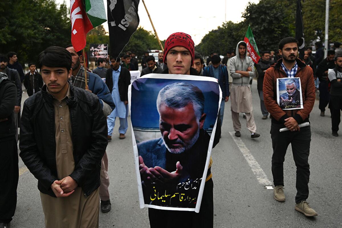 Protesters carry posters with the image of slain Iranian Gen. Qassem Suleimani during a demonstration in Islamabad, Pakistan, on Friday.  