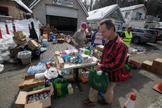 CRESTLINE, CA - MARCH 07: Valley of Enchantment resident Bill Roberts walks away with food and supplies from a volunteer food pantry in the San Bernardino Mountain community on Tuesday, March 7, 2023 in Valley of Enchantment, CA. (Brian van der Brug / Los Angeles Times)
