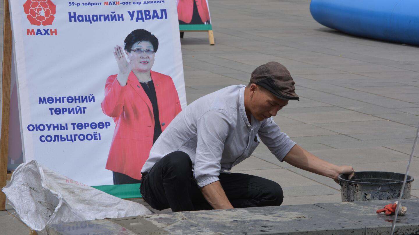 A worker makes repairs to a city fountain beside a campaign poster. Mongolia is gearing up for its eighth nationwide election since transitioning to democracy in 1990.