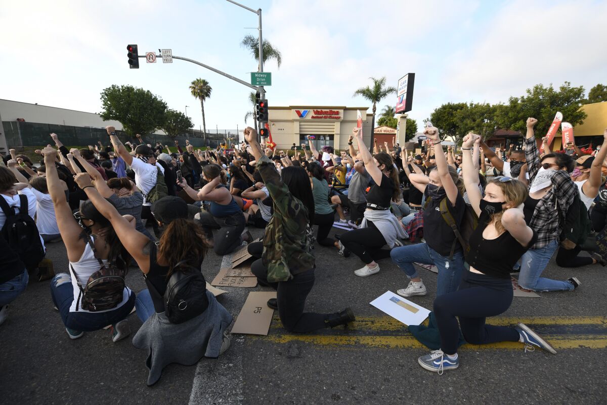 Protesters kneel down as they block Midway Dr. during a Black Lives Matter protest Wednesday, June 3, 2020 in San Diego.