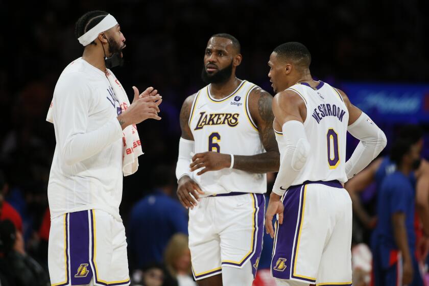 Los Angeles Lakers forwards Anthony Davis, left, and LeBron James, center, talk with guard Russell Westbrook during a timeout in the second half of an NBA basketball game against the Detroit Pistons Sunday, Nov. 28, 2021, in Los Angeles. (AP Photo/Alex Gallardo)