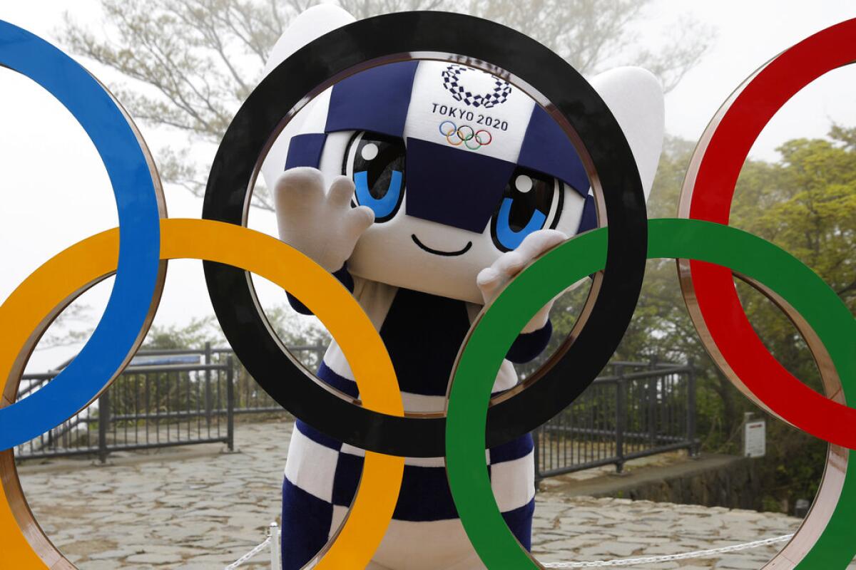 En esta imagen, tomada el 14 de abril de 2021, la mascota de Tokio 2020, Miraitowa, posa con los aros olímpicos 