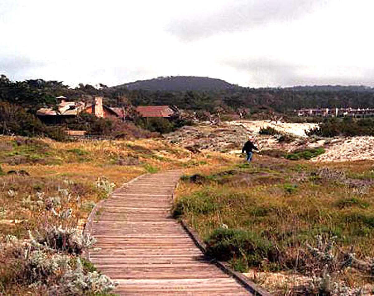 A boardwalk traverses the dunes fronting the stone, shake and redwood buildings at Asilomar Conference Grounds in Pacific Grove.