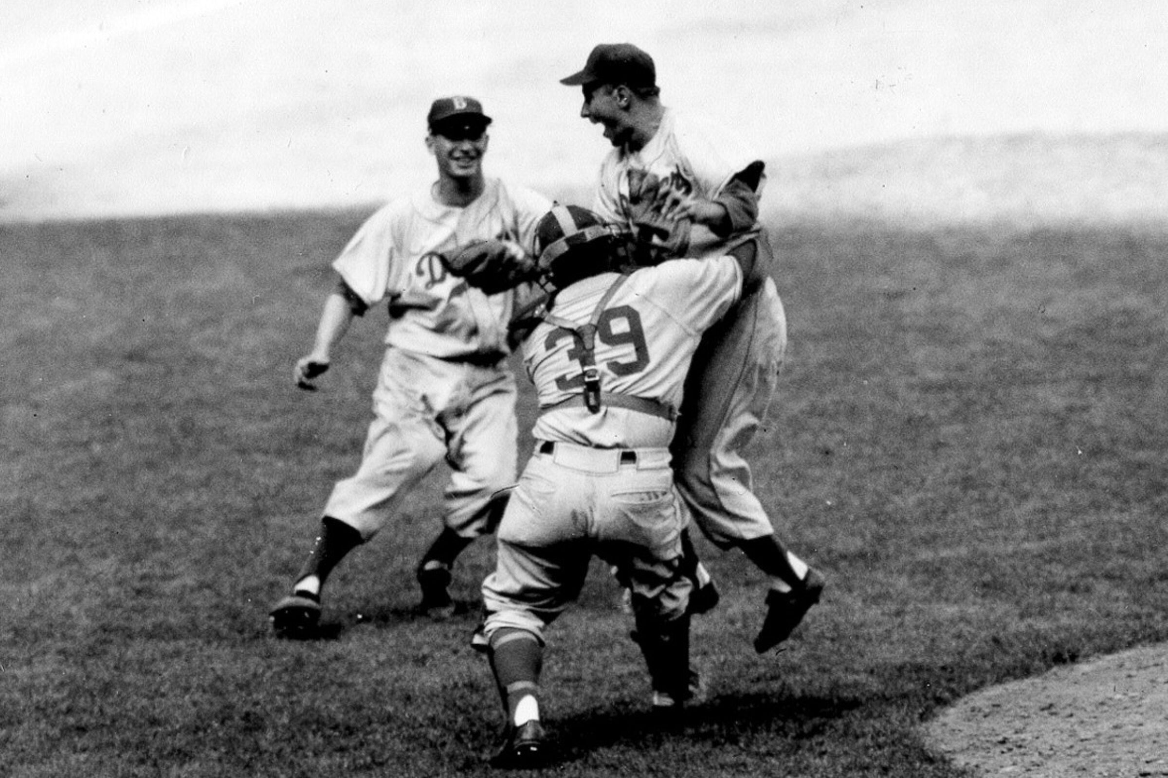 Brooklyn Dodgers pitcher Johnny Podres is lifted by catcher Roy Campanella.