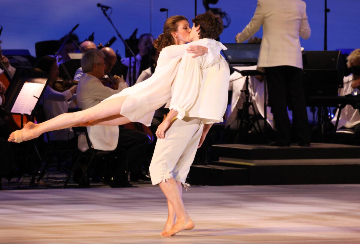 Two dancers embrace on the Hollywood Bowl stage during a Paris Opera Ballet performance conducted by Dudamel.