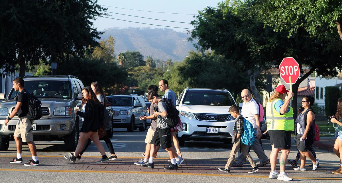 Parents and students of Toll Middle School, Mark Keppel Visual and Performing Arts Magnet School and Hoover High School cross Virginia Avenue in Glendale on the first day of school on Monday, Aug. 11, 2014. The Glendale Unified School District is considering pushing back the start of the school year after receiving a petition from parents.