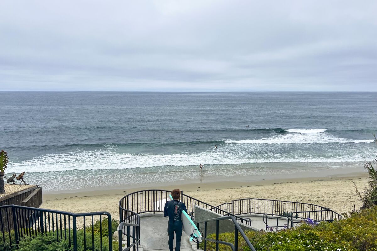 A surfer walks down the steps into Thalia Street Beach.