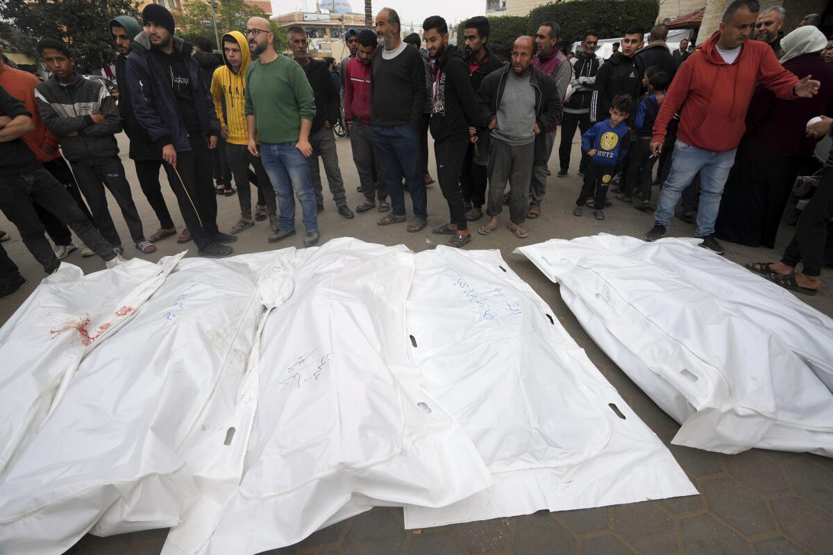 People weep over a row of white-shrouded bodies in Gaza.