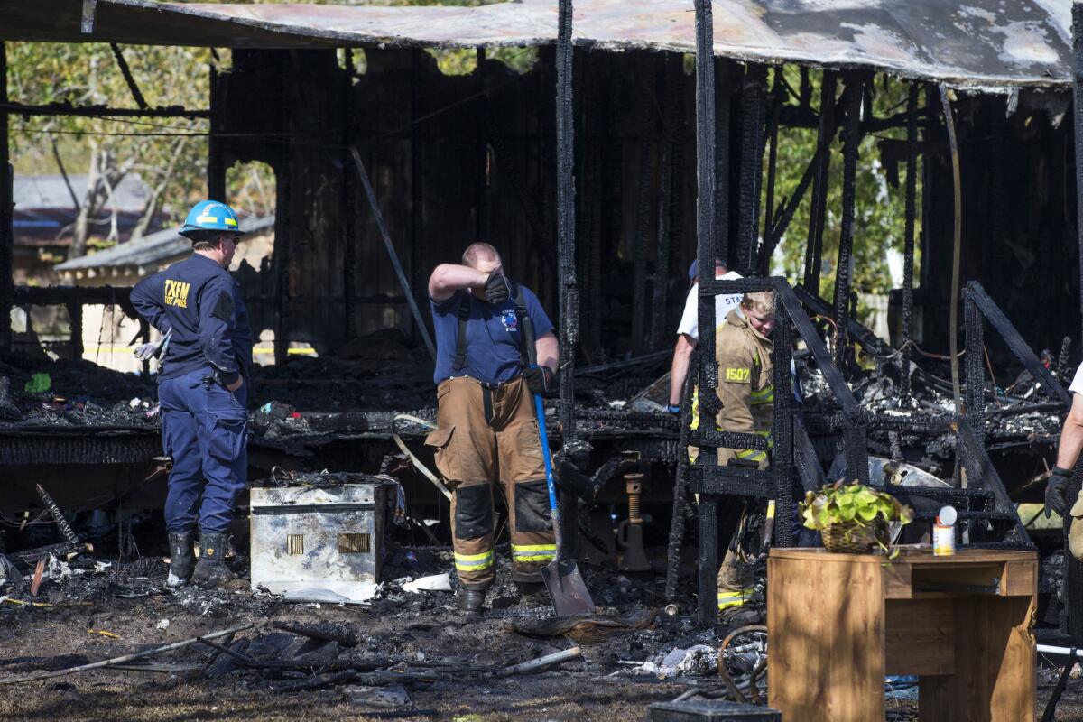 Firefighters sift through the charred remains of a mobile home in Edna, Texas, where five children perished in a fire on Nov. 25.