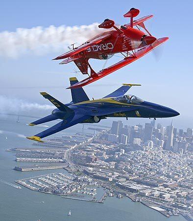 Sean Tucker flies his Oracle Challenger biplane over Marine Corps Maj. Nathan Miller's F/A-18 Blue Angel #5 above San Francisco Bay. Two air shows this weekend celebrate the area's naval history.