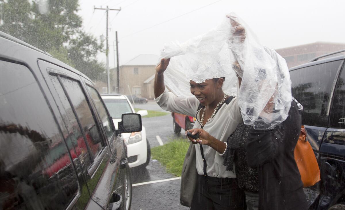 Women use a plastic sheet to try and stay dry in downtown Conroe, Texas. Heavy rains continue to hit the region.
