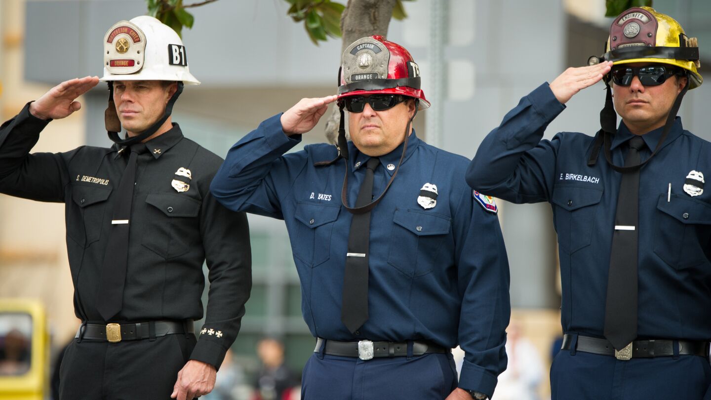 Fire personnel salute as the body of a slain Whittier police officer is driven from UC Irvine Medical Center to the coroners.