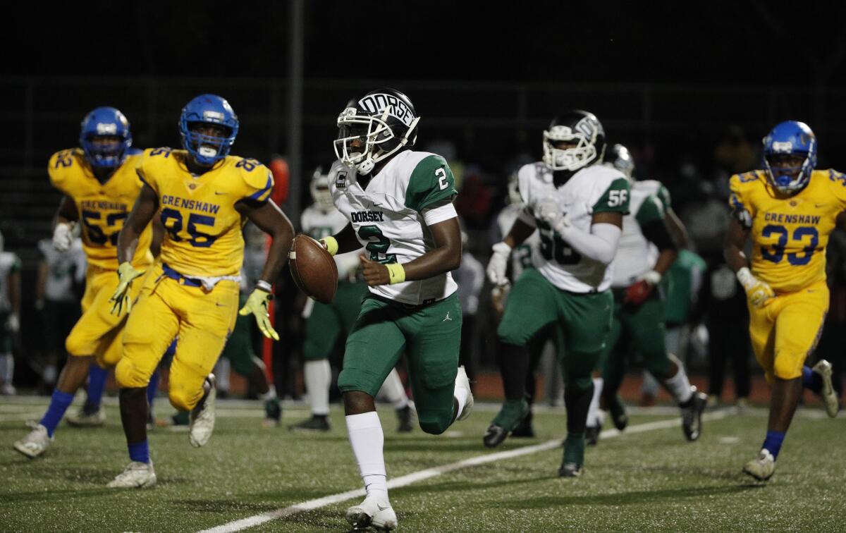 Dorsey quarterback Joshua Coleman runs toward the sideline to escape Crenshaw defenders during the first half.