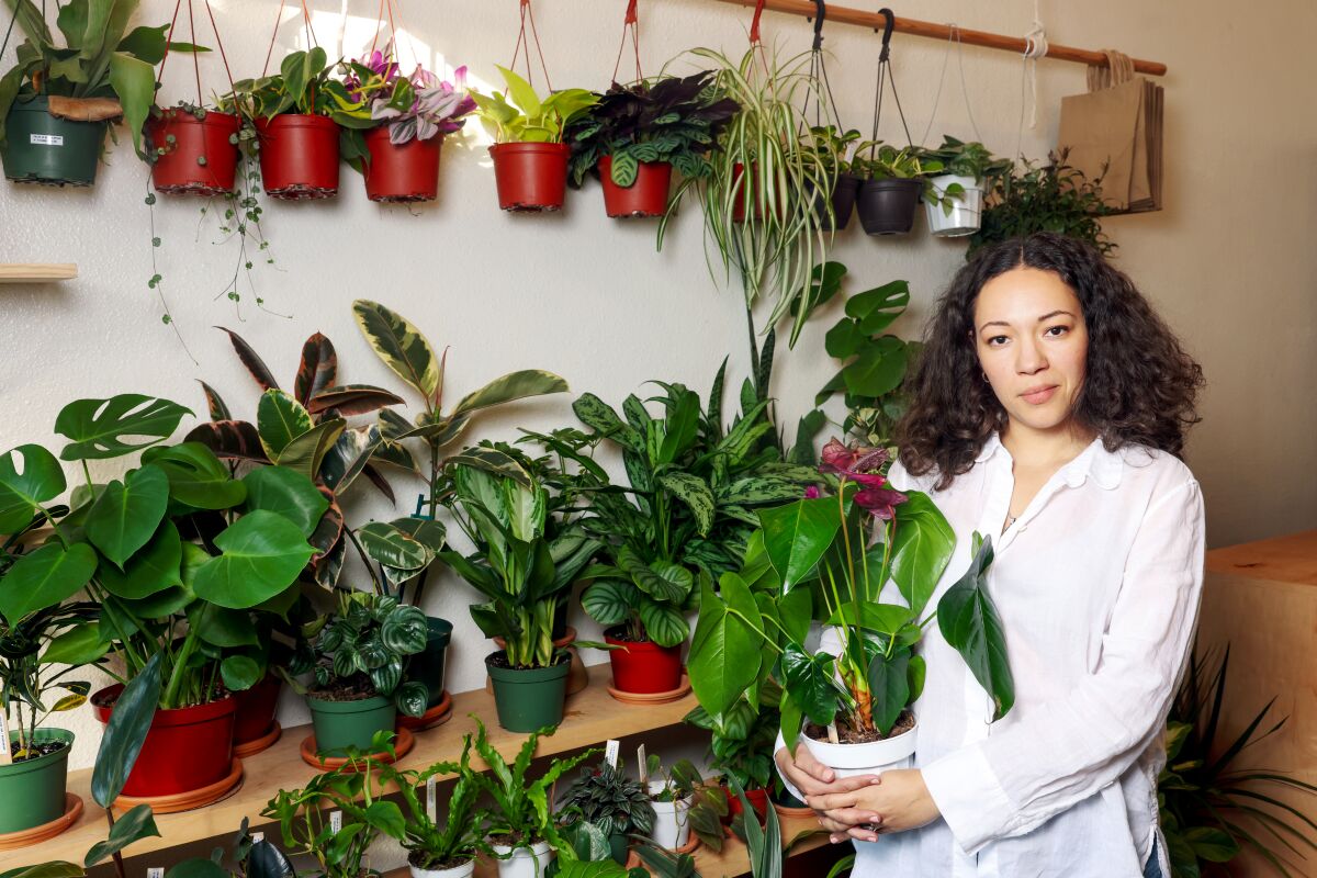 Sasha Pace holds a green plant with large leaves and waxy pink flowers 